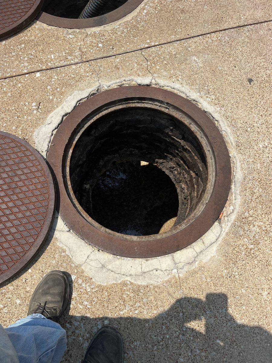 After outdoor grease trap cleaning, the open grease trap access shows the visible surface buildup removed after pumping.